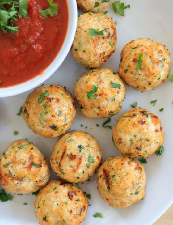 air fryer turkey meatballs on a white plate with marinara sauce in a bowl.