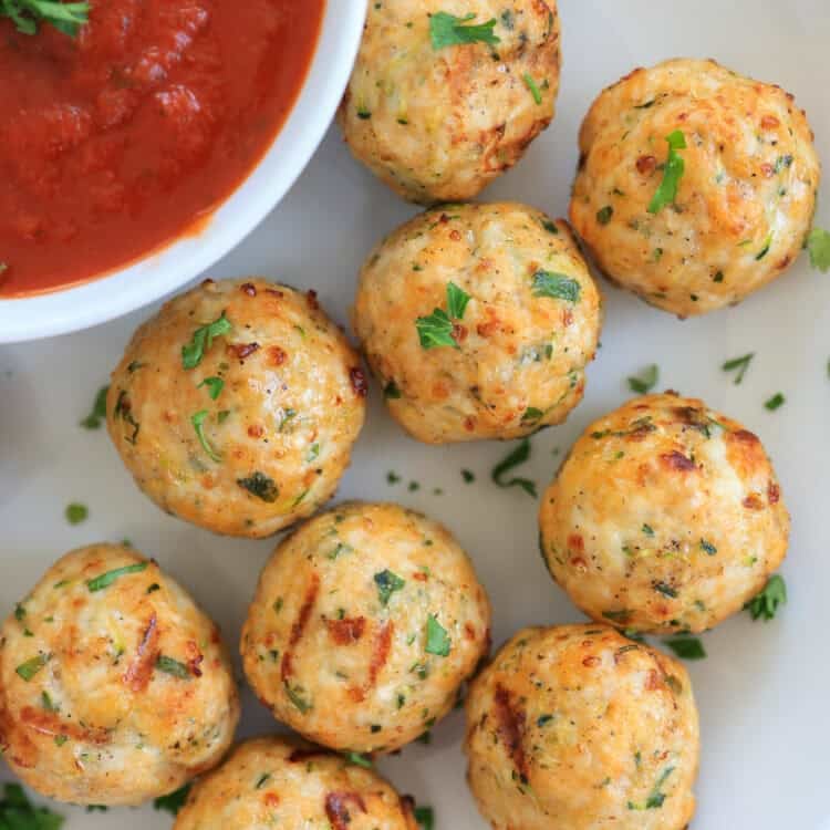 air fryer turkey meatballs on a white plate with marinara sauce in a bowl.