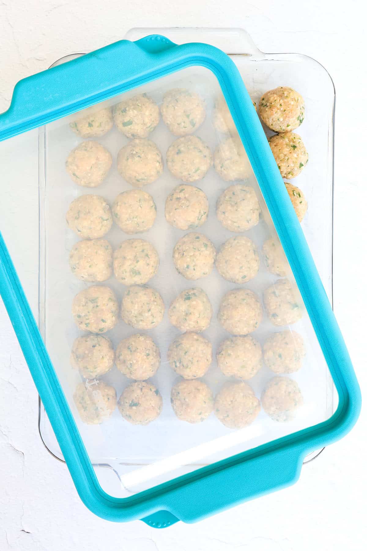 turkey meatballs prepped for the freezer in a glass freezer-friendly container with lid.