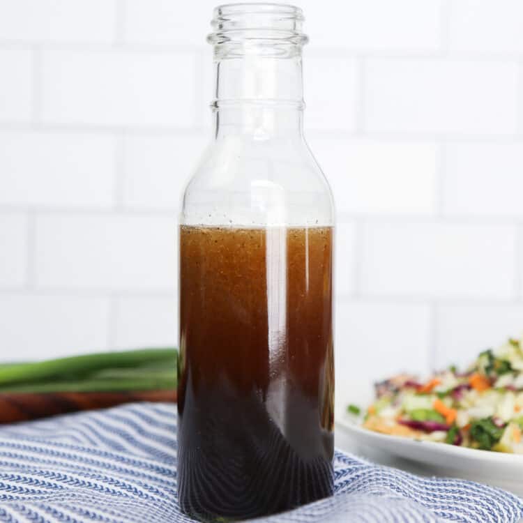 Asian Sesame Salad Dressing in a glass jar with a slaw salad in the background