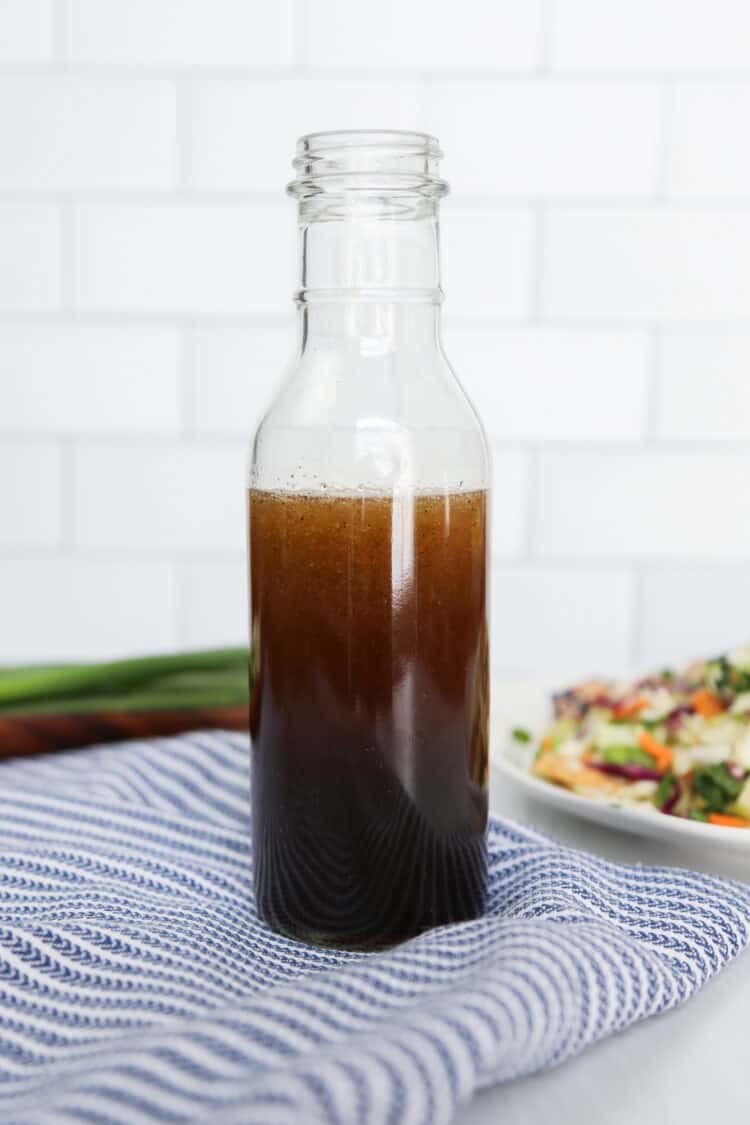 Asian Sesame Salad Dressing in a glass jar with a slaw salad in the background.