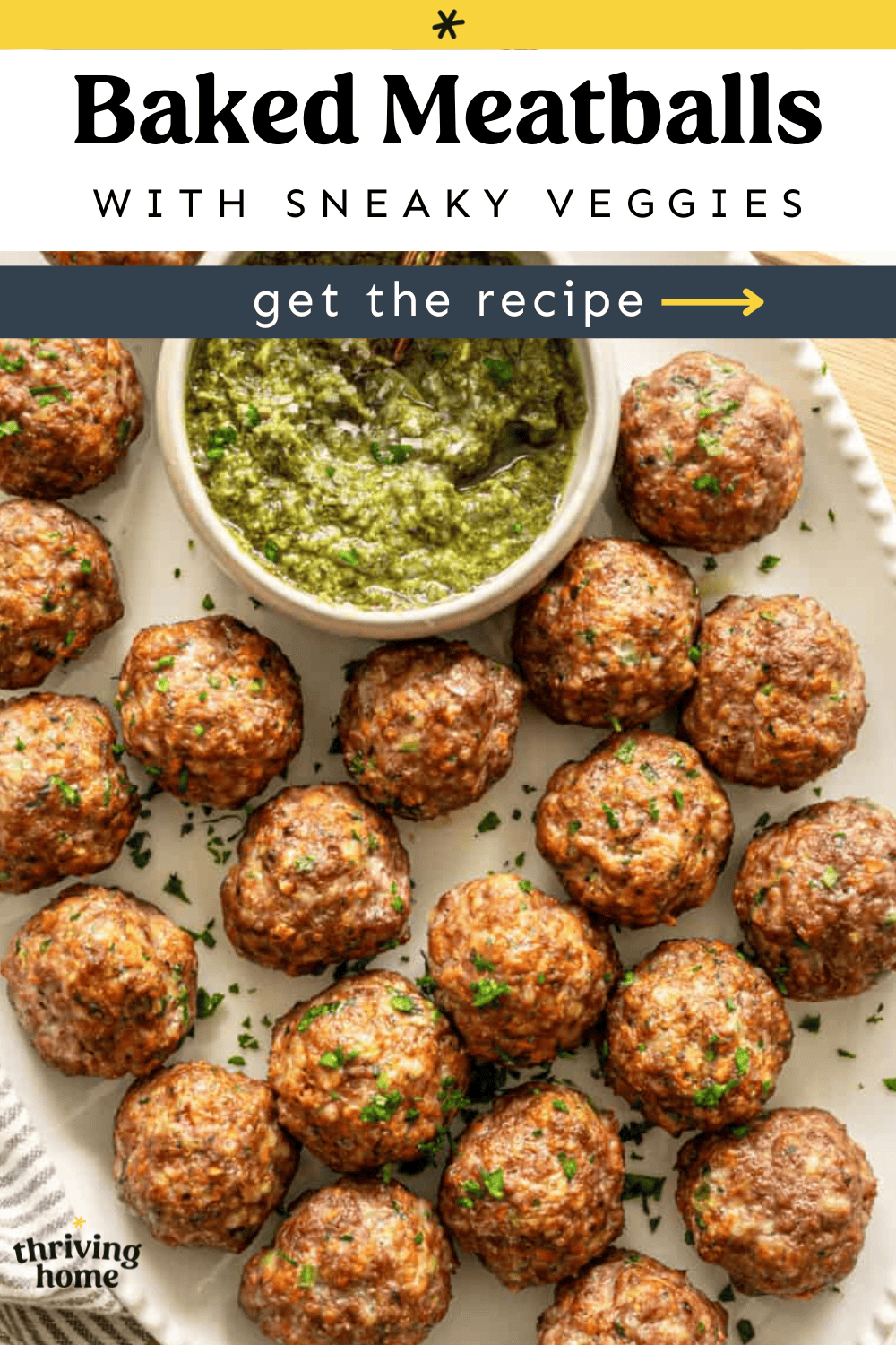 Baked meatballs with sneaky veggies on a platter with a bowl of pesto.