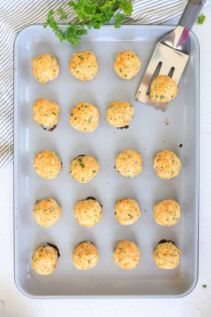 baked turkey meatballs on a sheet pan being served with a spatula.