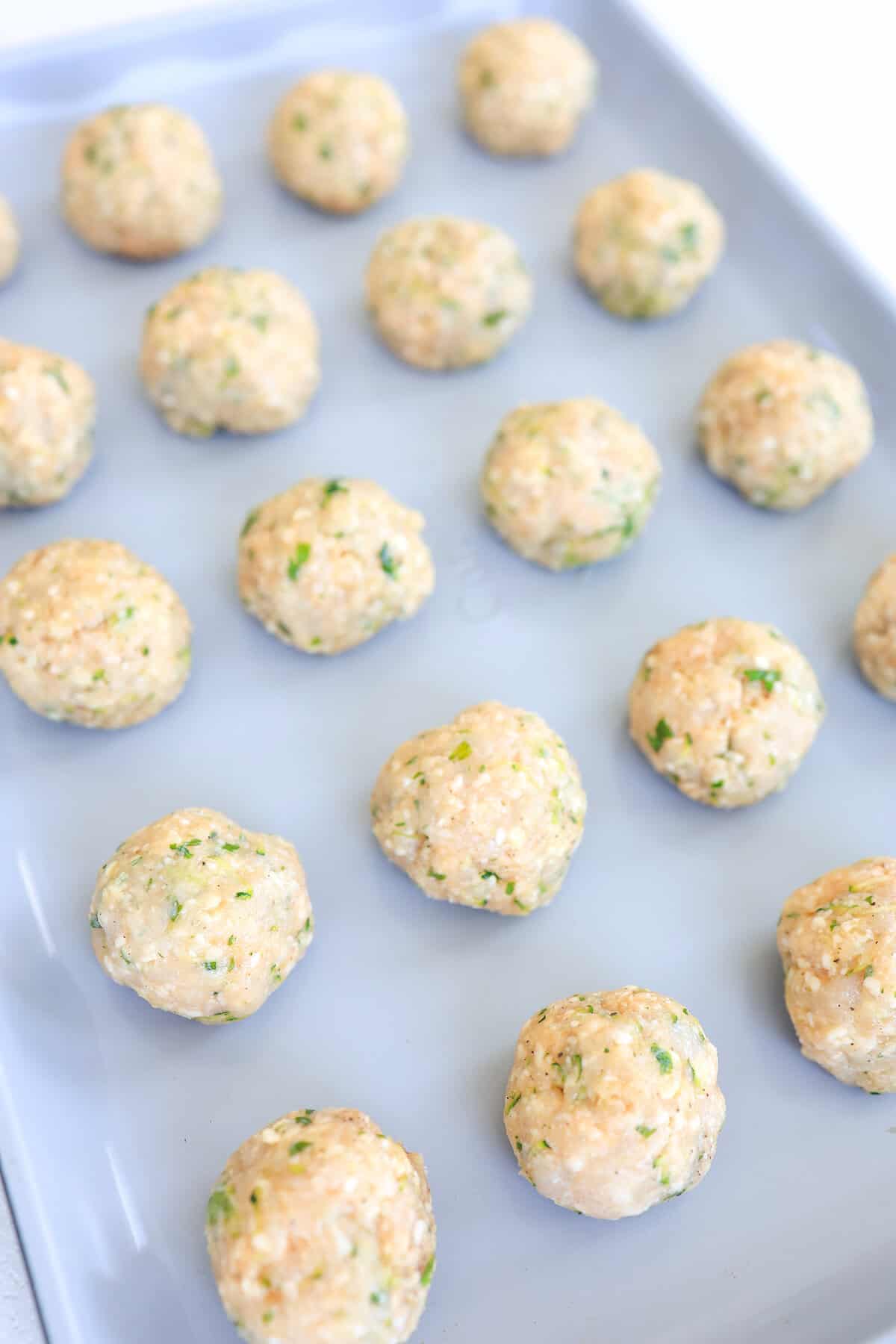 raw turkey meatballs on a sheet pan before baking.