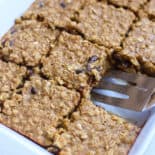 Banana baked oatmeal in a casserole dish sliced into squares with one missing.