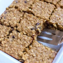 Banana baked oatmeal in a casserole dish sliced into squares with one missing.
