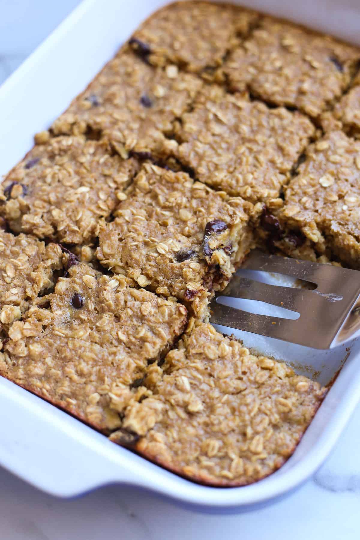Banana baked oatmeal in a casserole dish sliced into squares for serving.