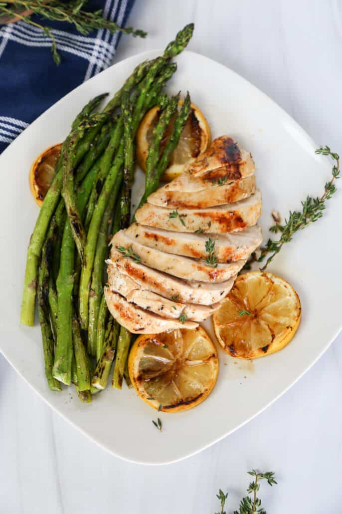Lemon garlic chicken sliced and laying on top of asparagus