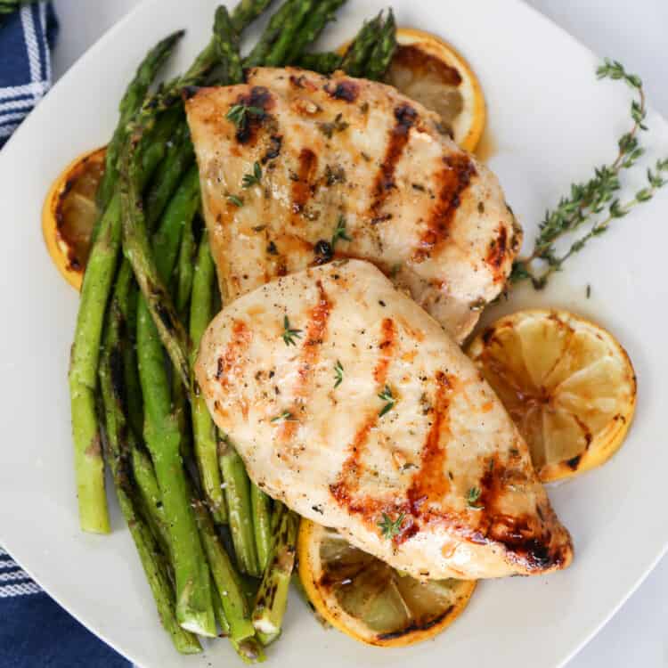 Grilled lemon garlic chicken on top of roasted asparagus and lemon slices.