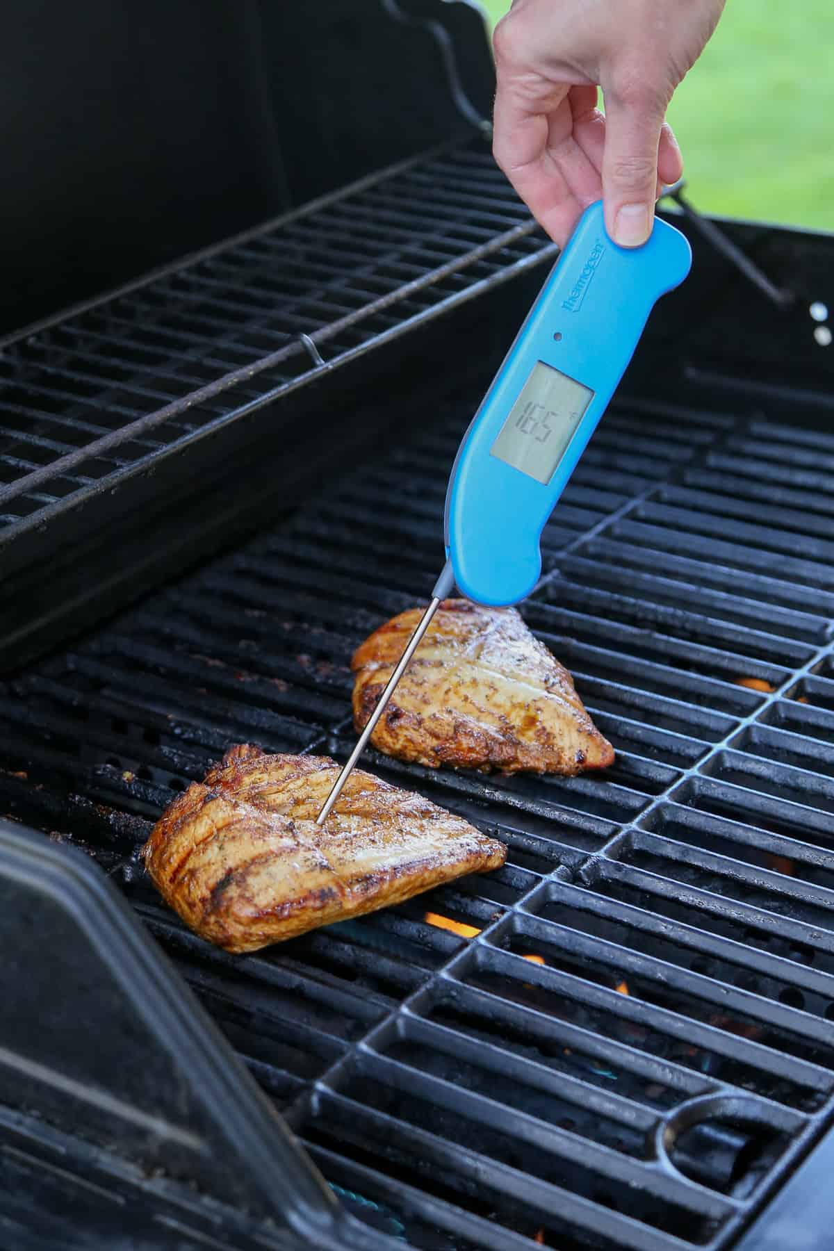 Meat thermometer in a chicken breast on a grill.