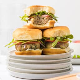Turkey burger sliders piled up on a stack of plates.