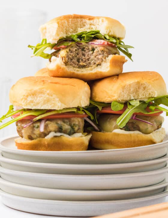 Turkey burger sliders piled up on a stack of plates.