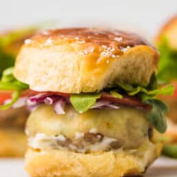 Air fryer chicken burgers with toppings on a pretzel bun.