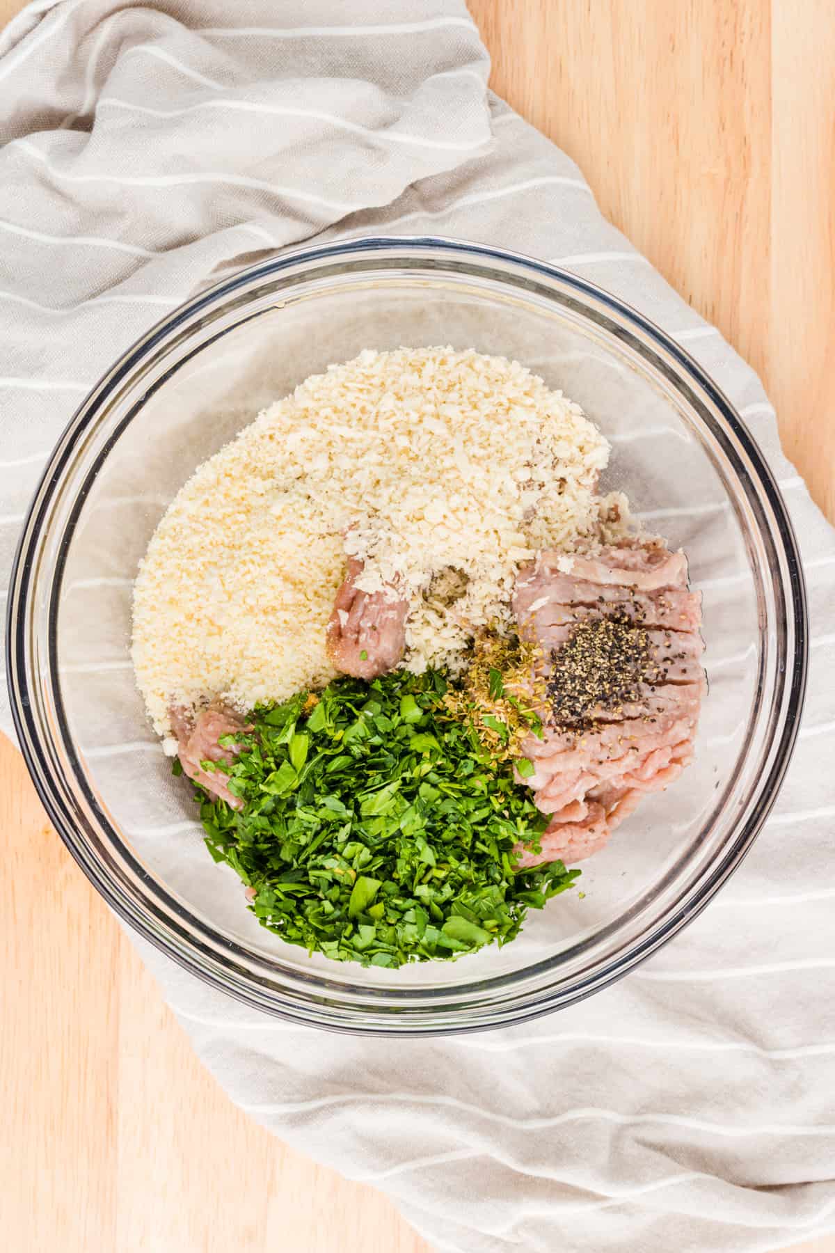 Chicken burger ingredients being mixed in a glass bowl.