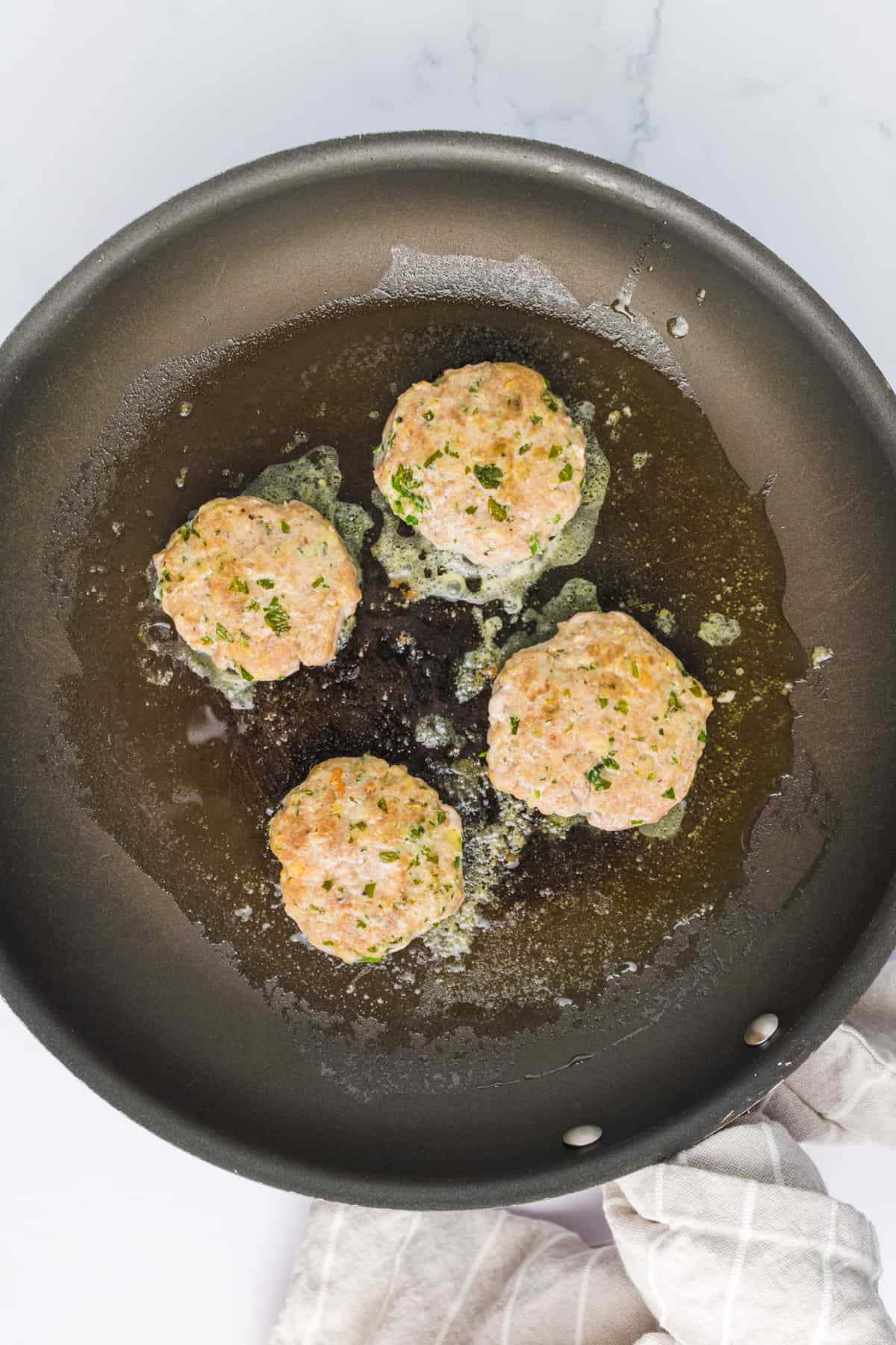 turkey burgers being cooked in a skillet