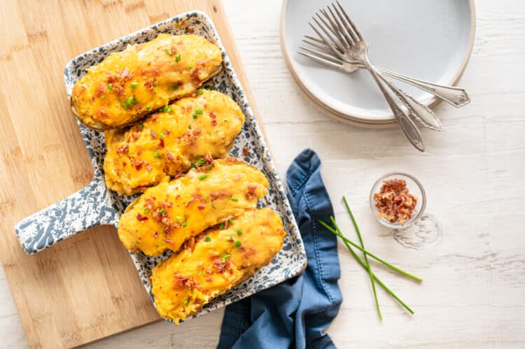 Twice baked potatoes lined up on a platter.