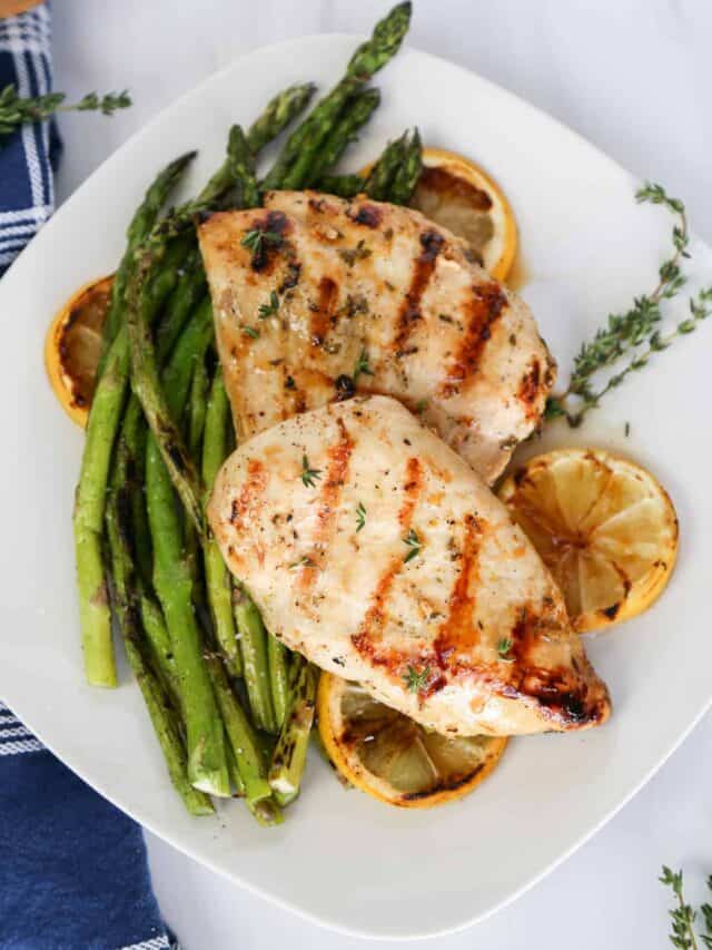 lemon garlic chicken on top of asparagus and lemon slices