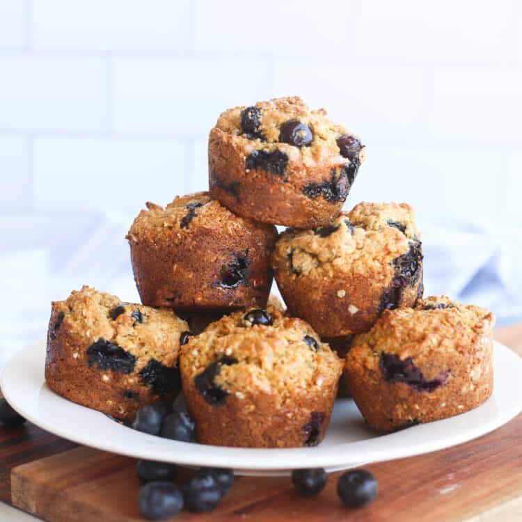 Blueberry oatmeal muffins stacked on a white plate.