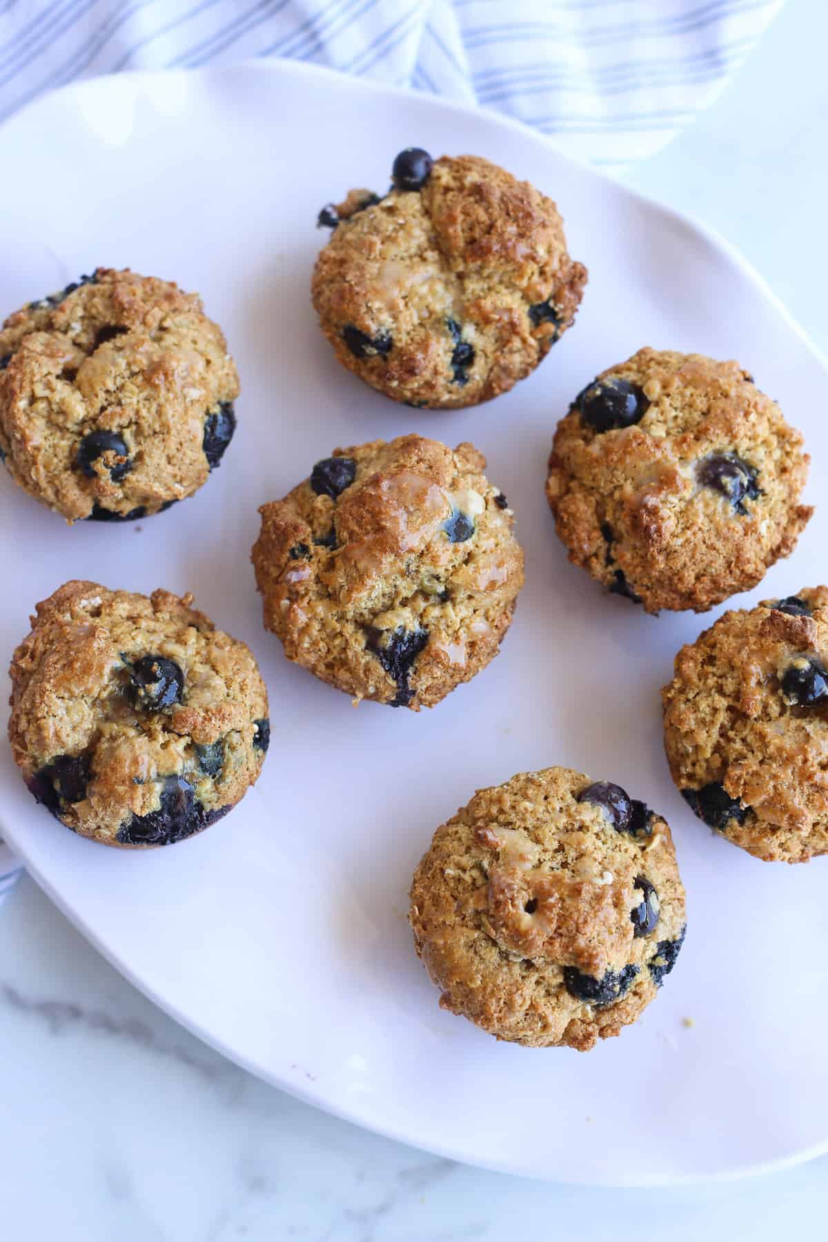 Blueberry oatmeal muffins cooling on a white platter.