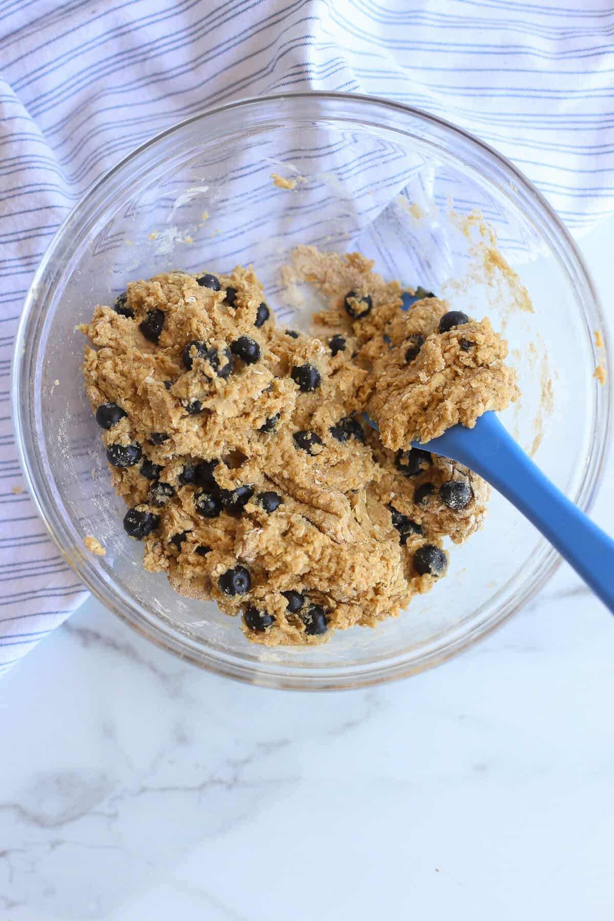 Batter for blueberry oatmeal muffins mixed together in a glass bowl.