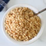 A bowl of gluten-free bread crumbs with a spoon.