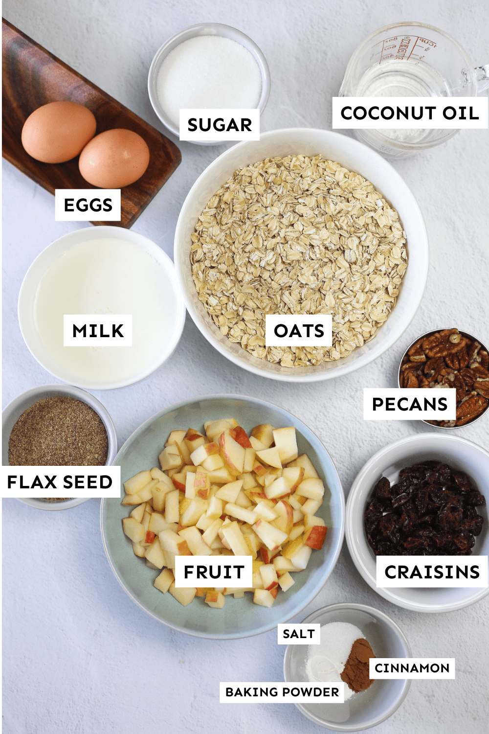 Ingredients for mixed fruit baked oatmeal measured in bowls and setting out on a counter.