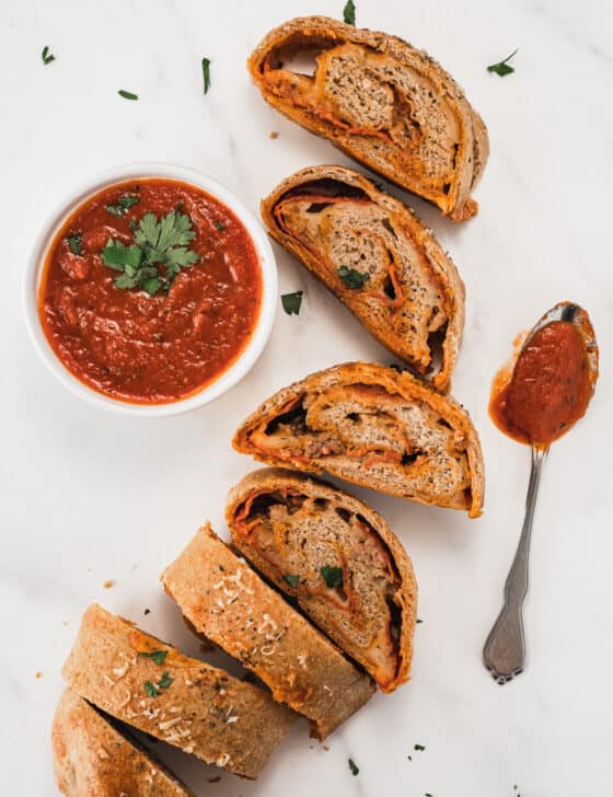 slices of stromboli pizza laid out with ramekin of marinara sauce