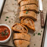Sliced Stromboli Pizza on a baking sheet with marinara