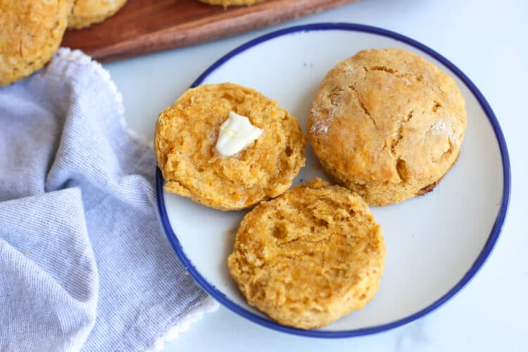 Sweet potato biscuits on a plate. One is buttered.