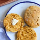 Sweet potato biscuits on a plate with one buttered.