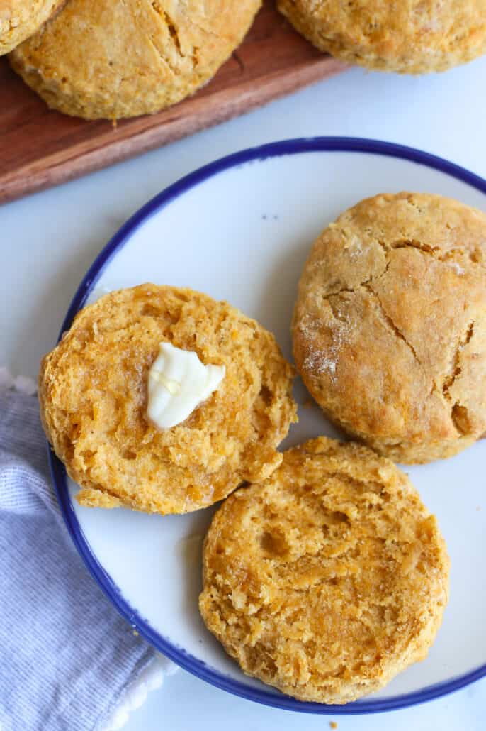 Sweet potato biscuits on a plate. One is buttered.