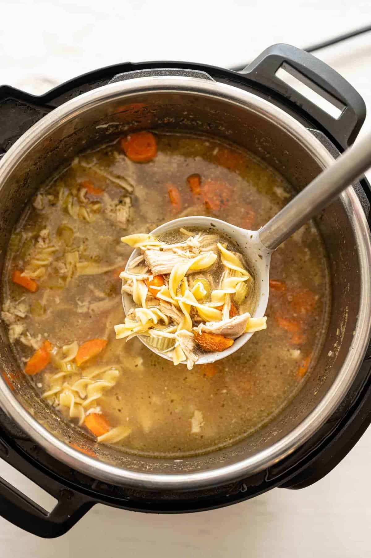 Instant Pot filled with chicken noodle soup with a serving ladle.