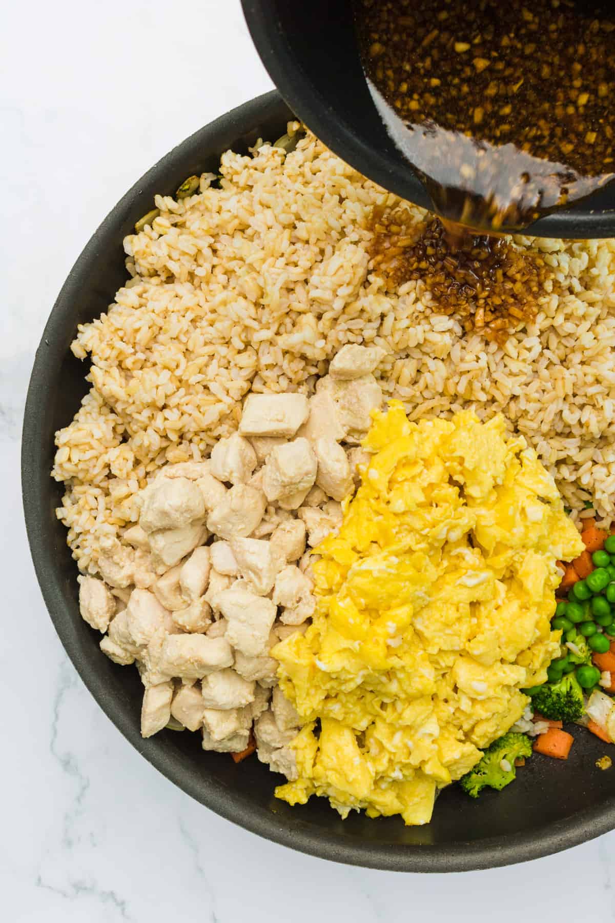 all cooked ingredients for healthy, easy chicken fried rice in individual piles in a big skillet