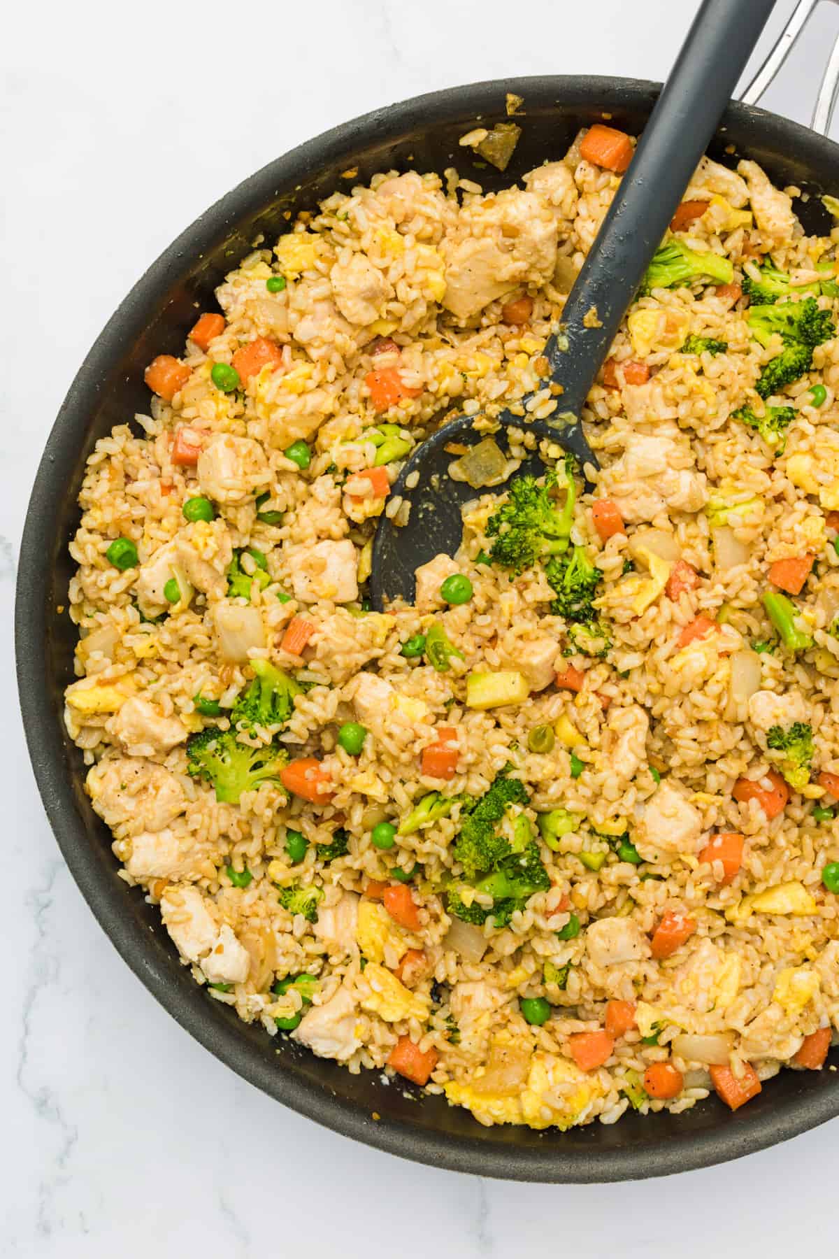 all ingredients for healthy, easy chicken fried rice are stirred together in a large skillet with a serving spoon
