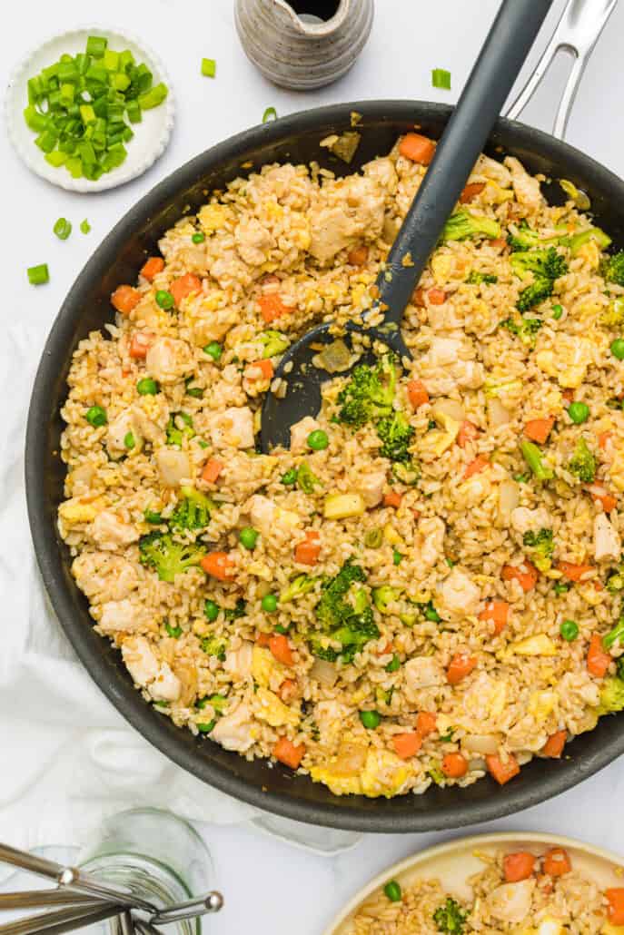 healthy, easy chicken fried rice in a skillet with a serving spoon