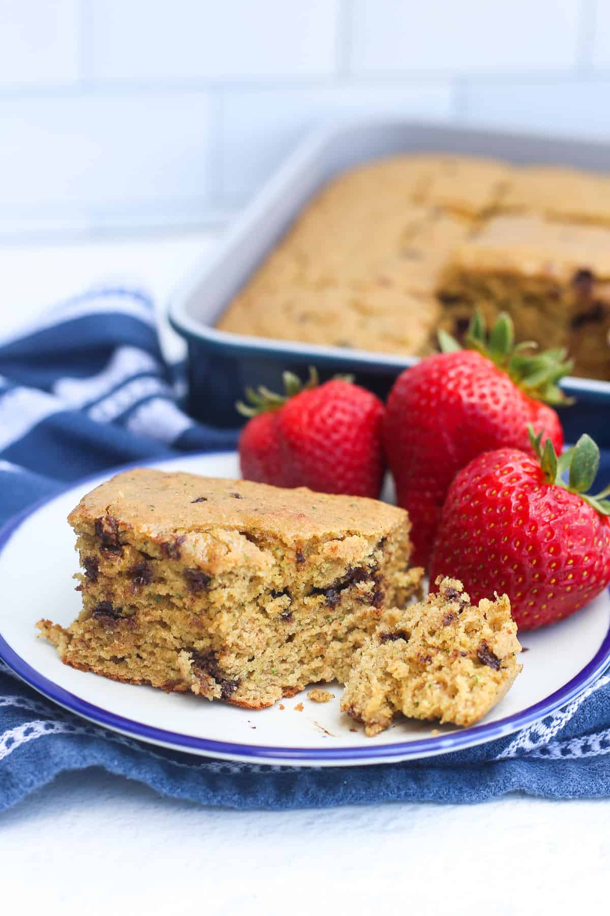 piece of zucchini breakfast cake on a plate with strawberries