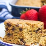 A piece of zucchini breakfast cake on a plate with strawberries.