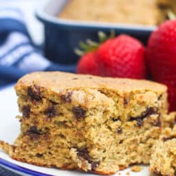 A piece of zucchini breakfast cake on a plate with strawberries.