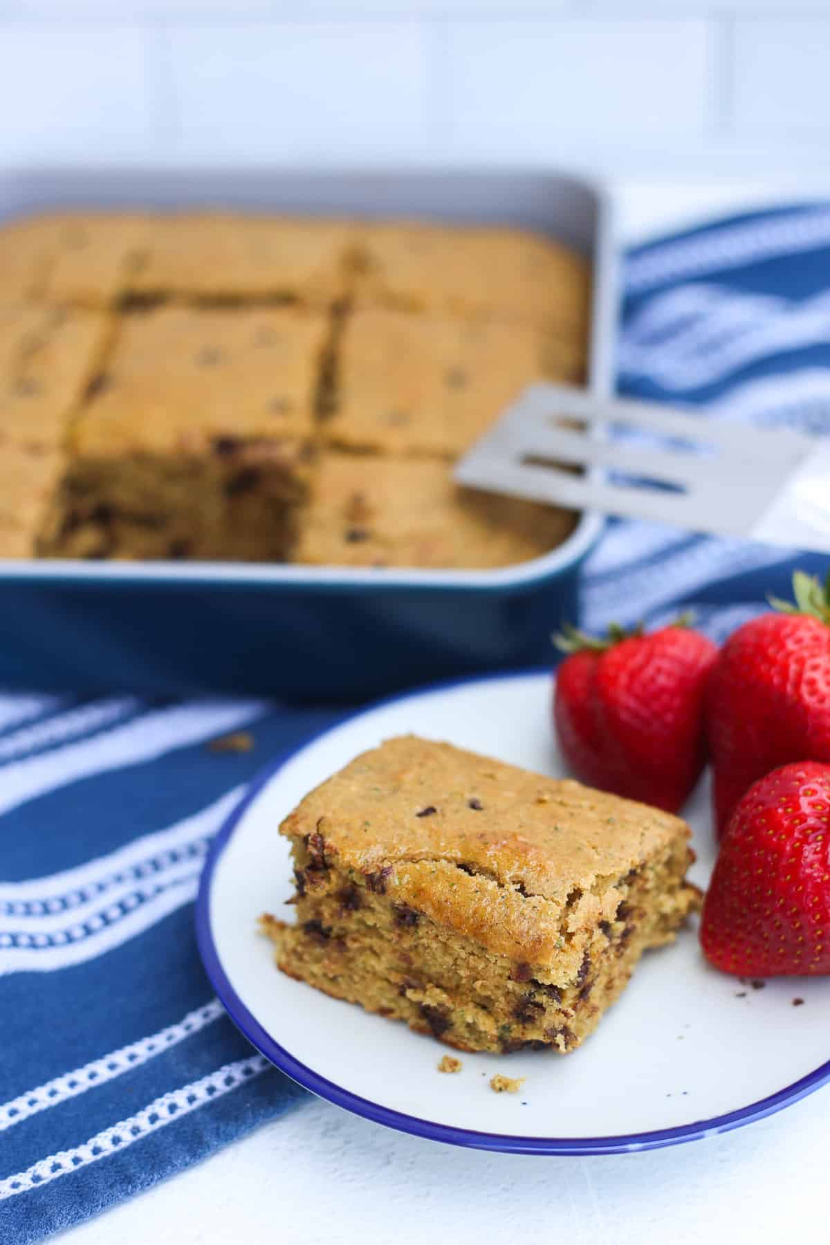 zucchinic breakfast cake in a pan and one piece on a plate