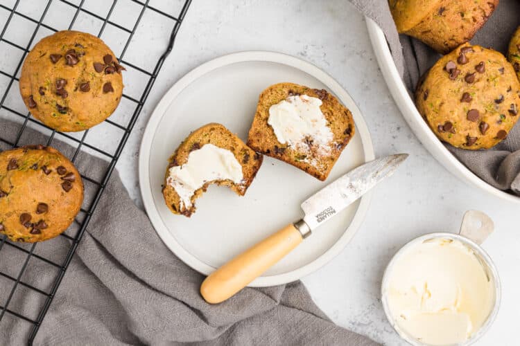 Chocolate Chip Zucchini Muffin cut in half with butter on a plate.