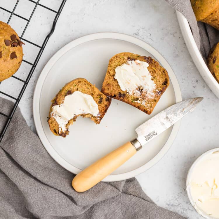 Chocolate Chip Zucchini Muffin cut in half with butter on a plate