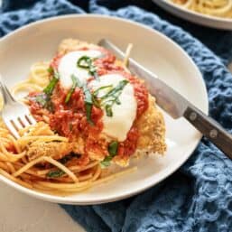 Baked Chicken Parmesan on plate with whole wheat noodles.