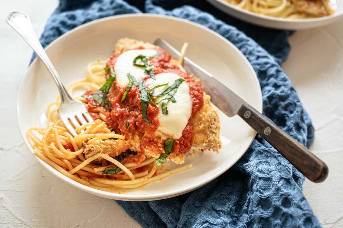 Baked Chicken Parmesan on plate with whole wheat noodles.