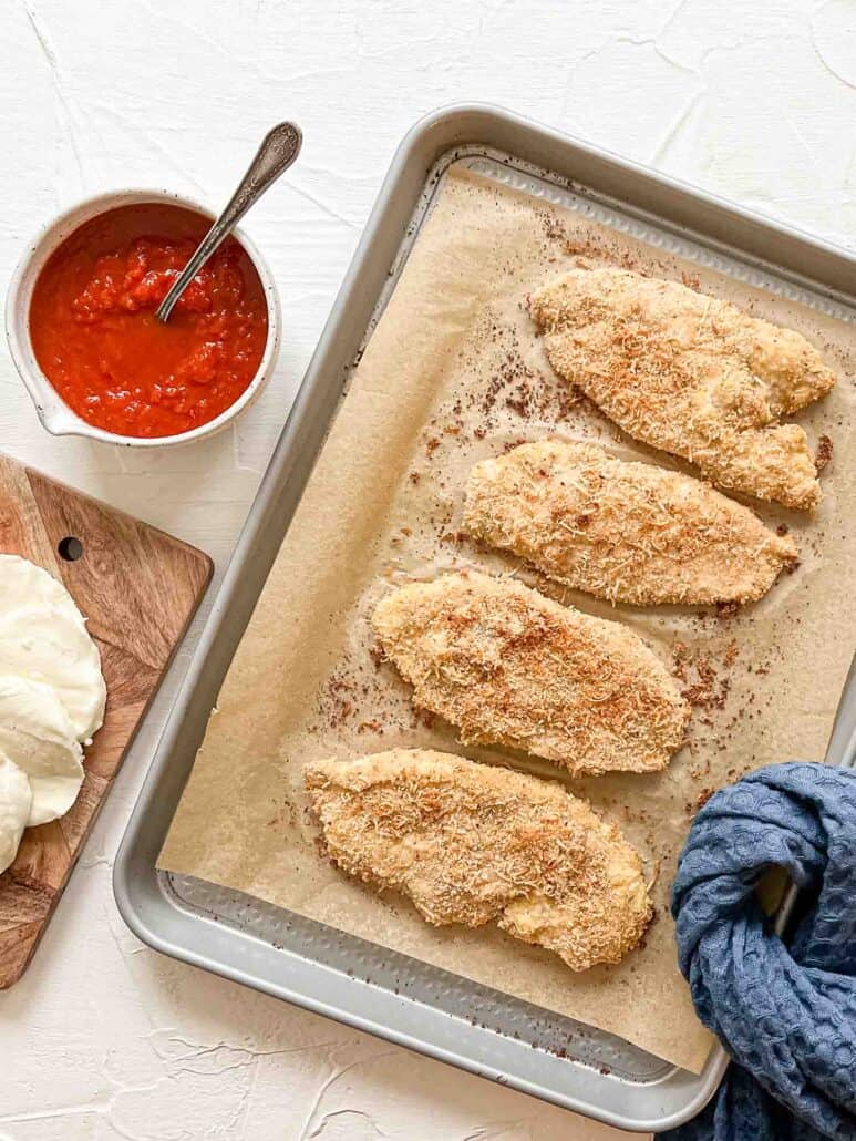 Breaded Chicken Breasts on baking sheet for Baked Chicken Parmesan