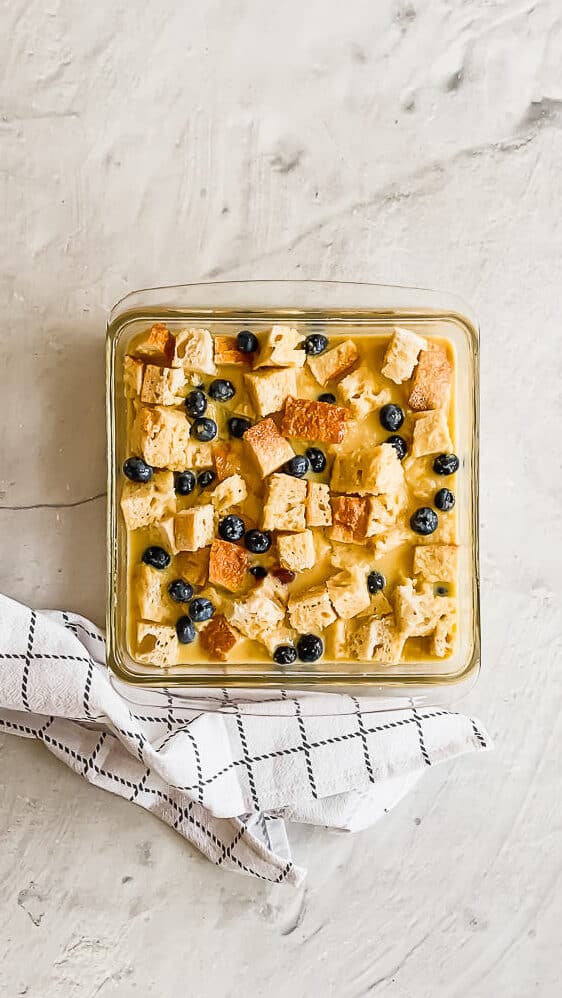 bread pieces and blueberries in a glass casserole dish