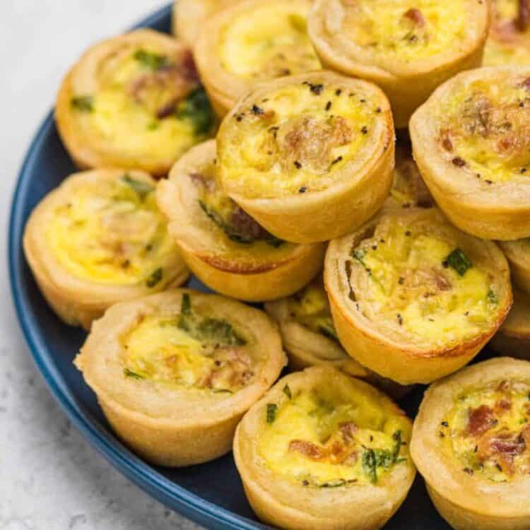 Baked Bacon and Spinach Mini Quiche stacked up on a plate.