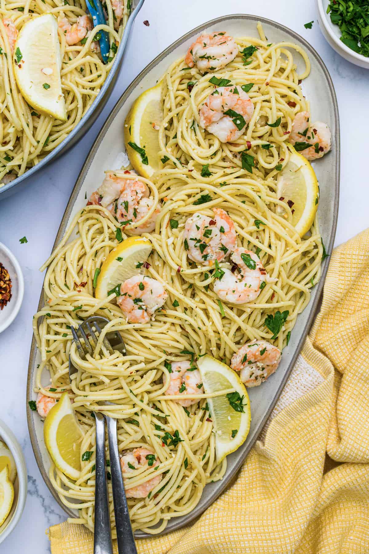 Shrimp Scampi pasta on a serving platter with a fork and spoon.