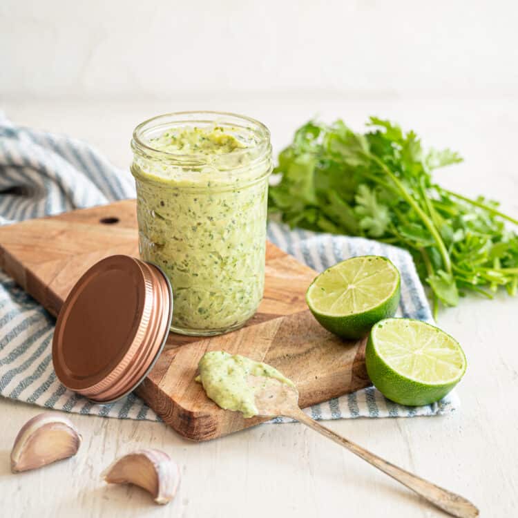 Cilantro Lime Aioli in a small mason jar sitting on a wooden cutting board.