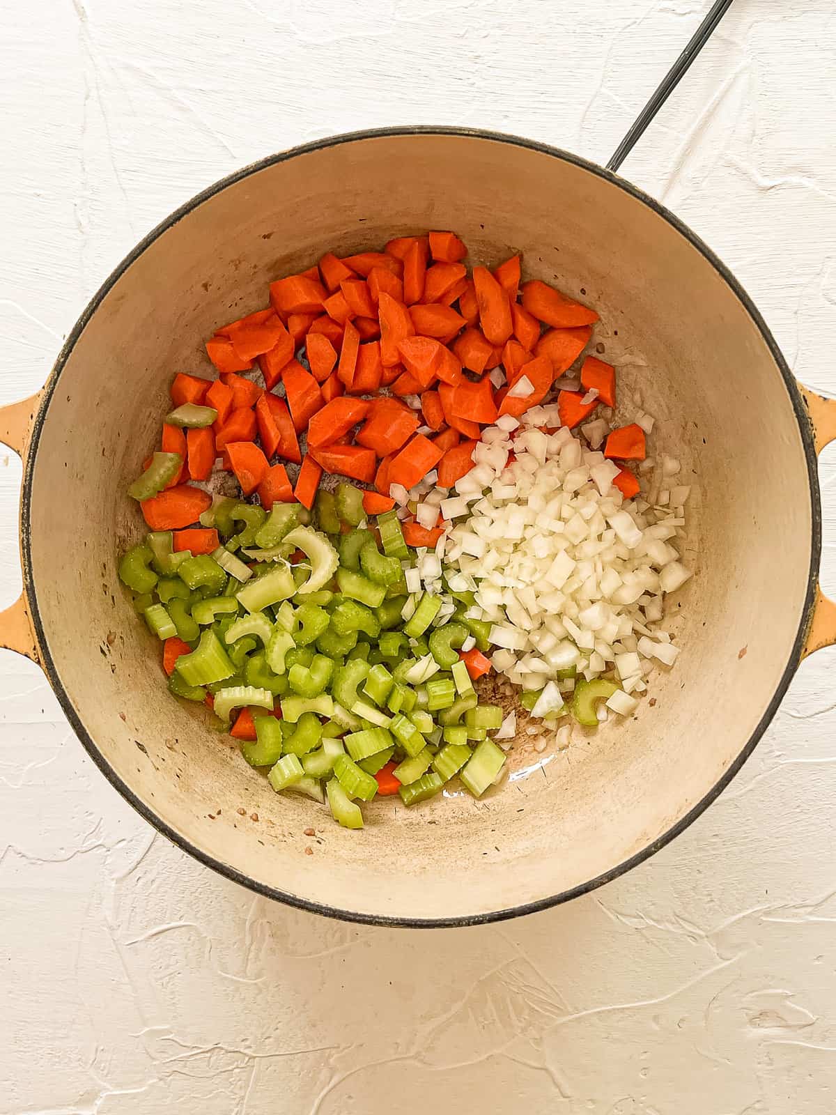 Chopped carrots, onions, and celery in a dutch oven.