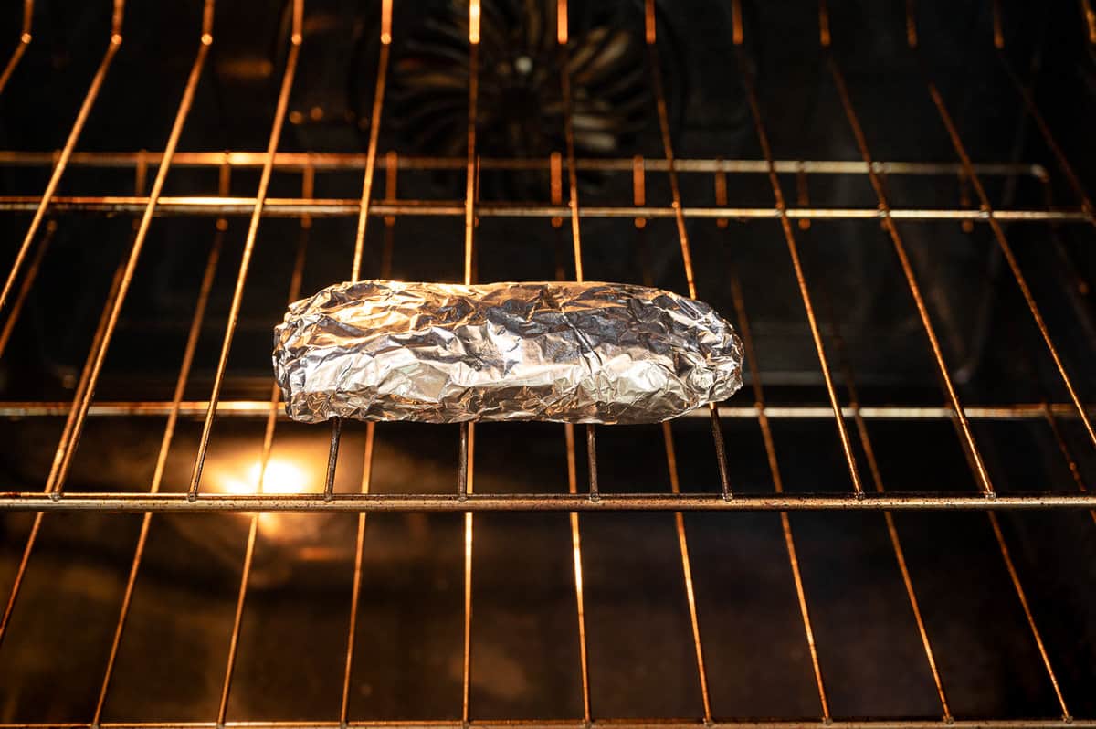 Chicken Burrito wrapped in foil inside an oven.